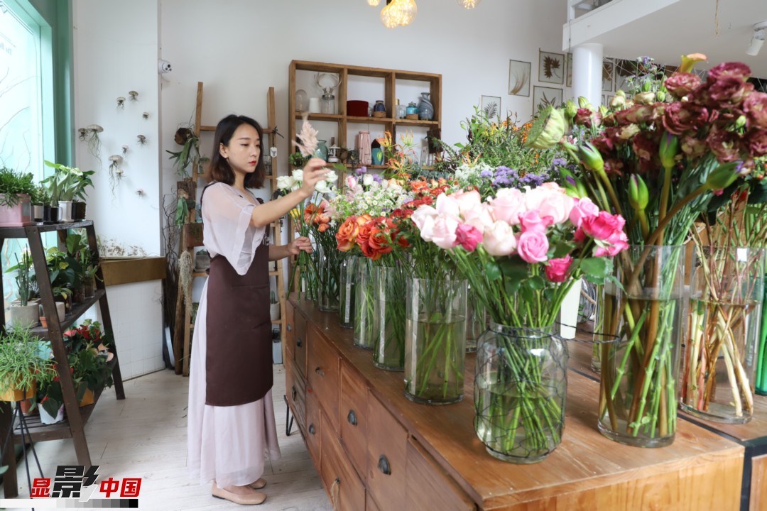 王黎媛是一名河南姑娘，在昆明念完大學后，就再也舍不下春城的藍天陽光、青山碧水，更舍不下這里的四時繁花，于是就干脆留了下來，成了一名媒體人。2017年的時候又毅然辭去工作，創(chuàng)業(yè)開起了花店，成了都市里的一名“花房姑娘”。圖為王黎媛在自己的花店中整理鮮花。新華網(wǎng) 周亞平/攝 念新洪/文